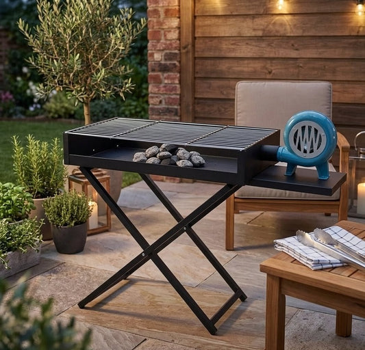 Portable outdoor folding charcoal BBQ grill with manual air blower, durable metal body, and spacious cooking surface for camping and home barbecues. 🔥