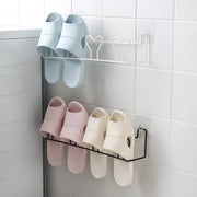 Wall-mounted self-adhesive slipper steel rack holding two pairs, space-saving shoe organizer in black or white.
