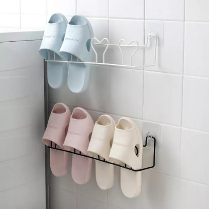 Wall-mounted self-adhesive slipper steel rack holding two pairs, space-saving shoe organizer in black or white.