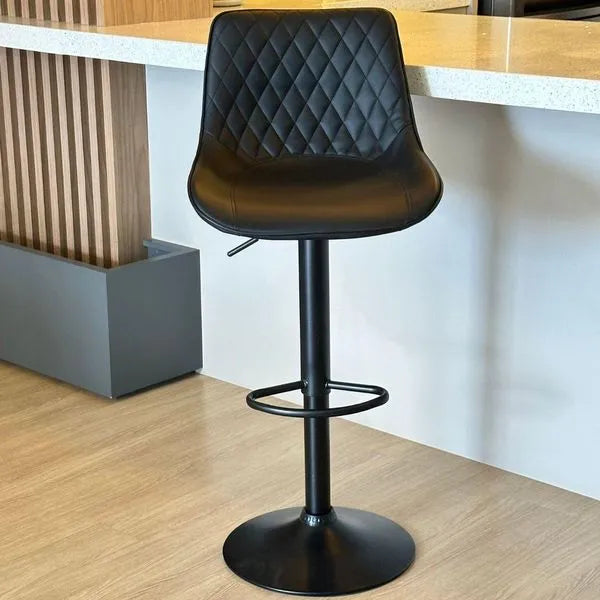 Black PU leather swivel bar stool with diamond quilted backrest, hydraulic height adjustment, matte black base, and circular footrest
