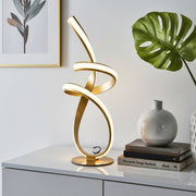 Gold ribbon LED table lamp with twisted modern design warm white ambient lighting and gold finish for bedside tables living rooms office desks and home décor.