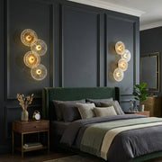 Modern wall-mounted decorative light fixture with four illuminated textured circular discs and warm golden glow. 