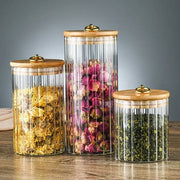 Glass storage containers with bamboo lids and golden pull rings in three sizes.