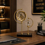 Golden celestial stand clock with a clear crystal ball globe for elegant tabletop home and office décor.