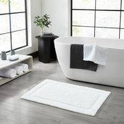 White plush cotton bath mat with skid-resistant backing for home or hotel use