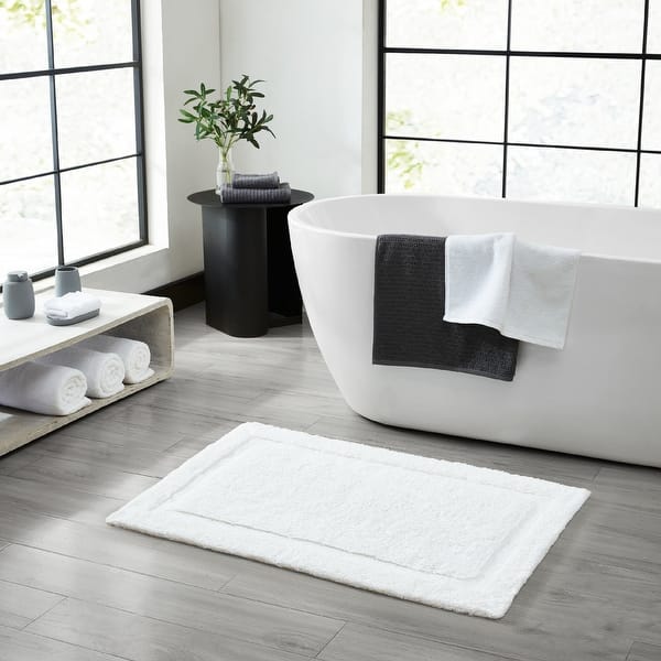 White plush cotton bath mat with skid-resistant backing for home or hotel use