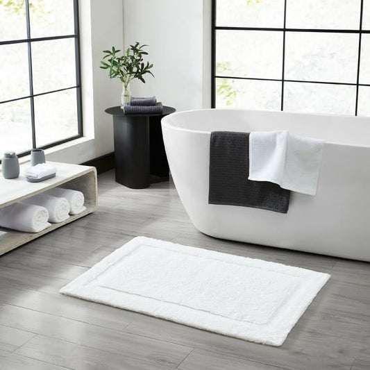 White plush cotton bath mat with skid-resistant backing for home or hotel use