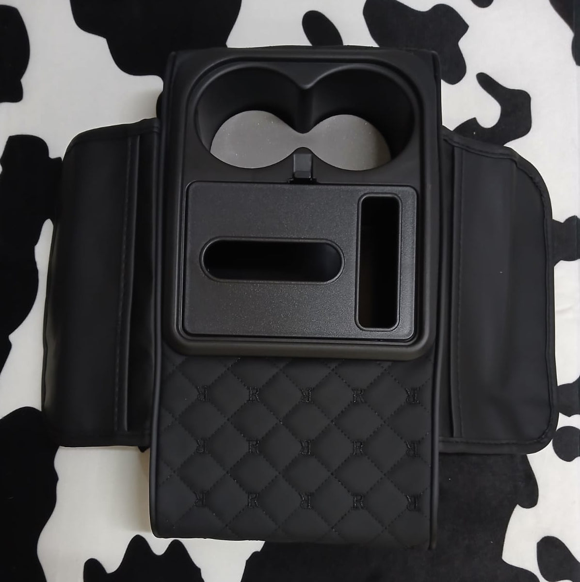 Black universal car console armrest storage organizer with dual cup holders, phone holder, multiple compartments, and padded armrest.