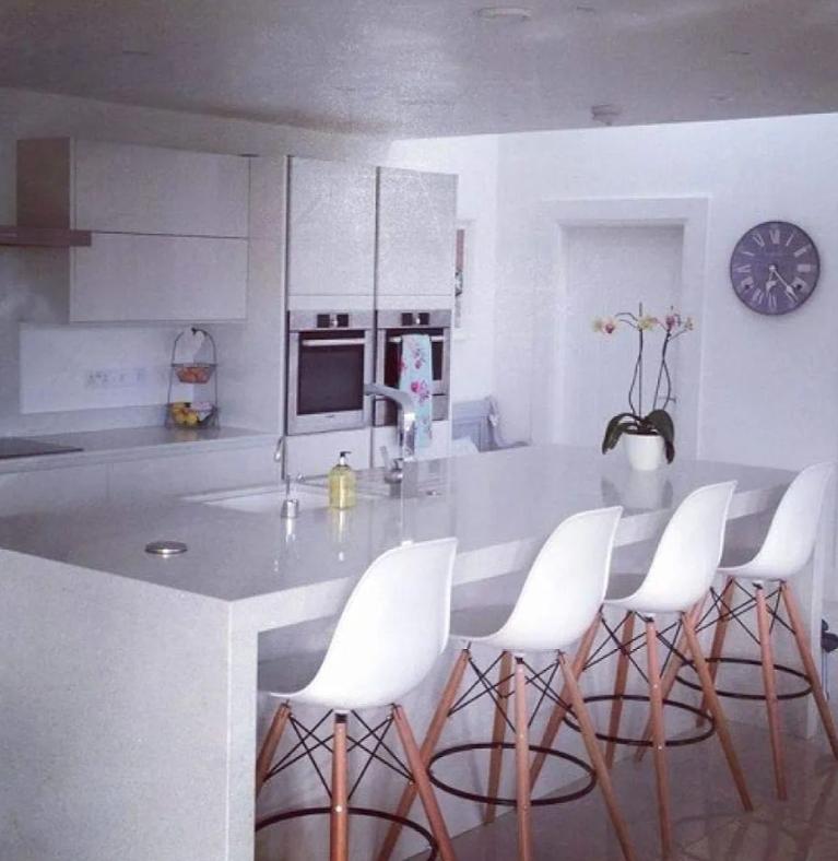 Eames Style DSW counter bar stool with a molded plastic seat, natural wood Eiffel legs, and a modern armless design.