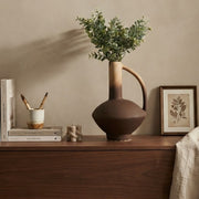 Two tone ceramic amphora vase with arched handle and dusty green artificial eucalyptus stems for interior décor.