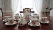 Bone tea set with pink flowers, yellow roses, butterfly patterns, and gold edges, including kettle, milk jug, sugar dish, 6 cups, and 6 saucers.