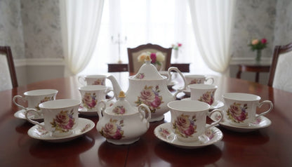 Bone tea set with pink flowers, yellow roses, butterfly patterns, and gold edges, including kettle, milk jug, sugar dish, 6 cups, and 6 saucers.