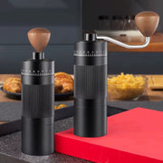 Handheld manual coffee grinder with stainless steel burr in black and silver.