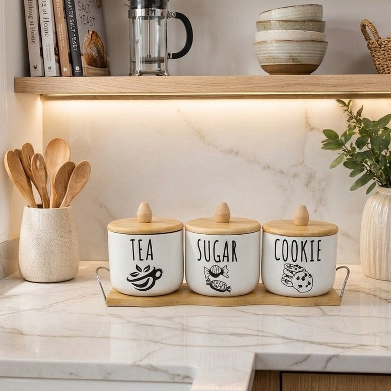 Four piece kitchen canister set with tray and wooden lids for storing tea, sugar, coffee, and cookies.