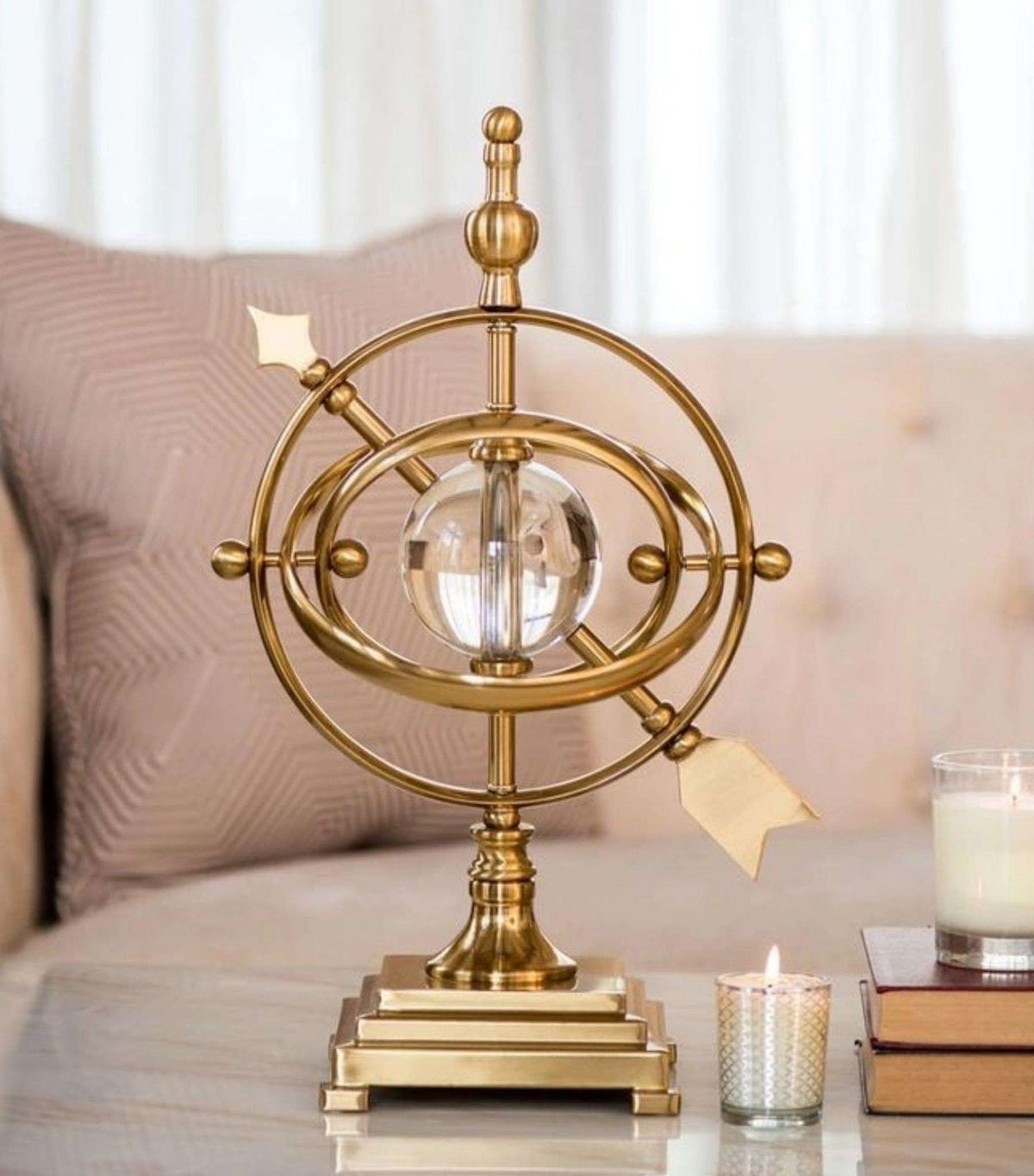 Dawood Lifestyle & Gadgets kes gold armillary sphere sculpture with rotating metal rings and clear crystal ball centre mounted on a tiered gold display base.