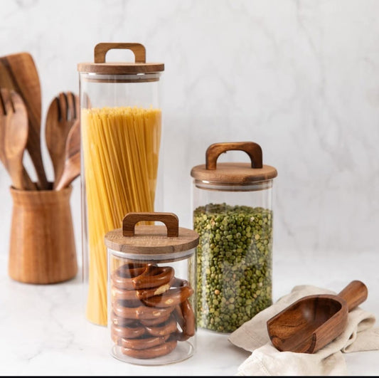 Three clear borosilicate glass storage jars with bamboo lids arranged on a kitchen counter