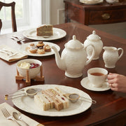 39 piece white porcelain dinner set with embossed design and gold rim, including plates, bowls, cups, saucers, oval platters, and kettle.