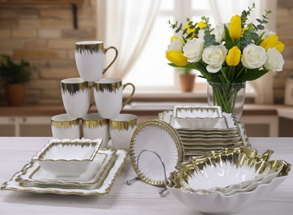 33 piece white ceramic dinner set with gold detailing, including plates, bowls, mugs, saucers, and leaf serving bowls