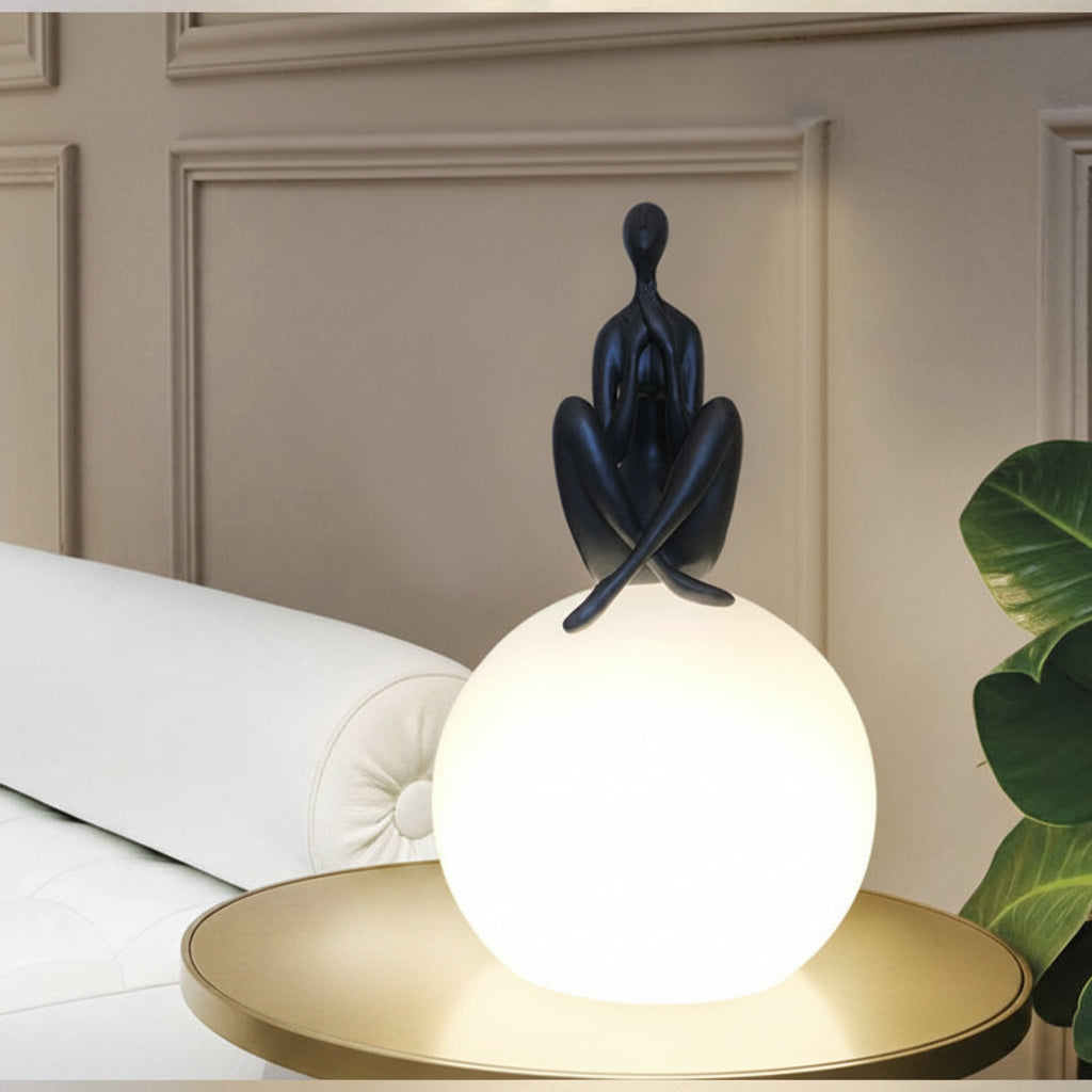 Dawood Lifestyle & Gadgets kes Zen yoga sculpture globe lamp featuring a matte black meditating figure seated on a glowing white LED globe, modern decorative table light for living rooms, bedrooms, offices, and wellness spaces.