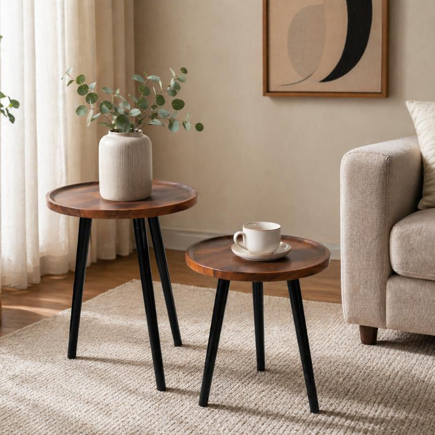 Twin round nesting coffee tables with dark wood look tops and black metal legs, modern space saving set.