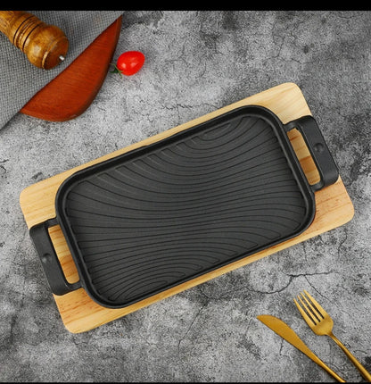 Rectangular cast iron sizzling grill pan with wooden base for serving hot meals
