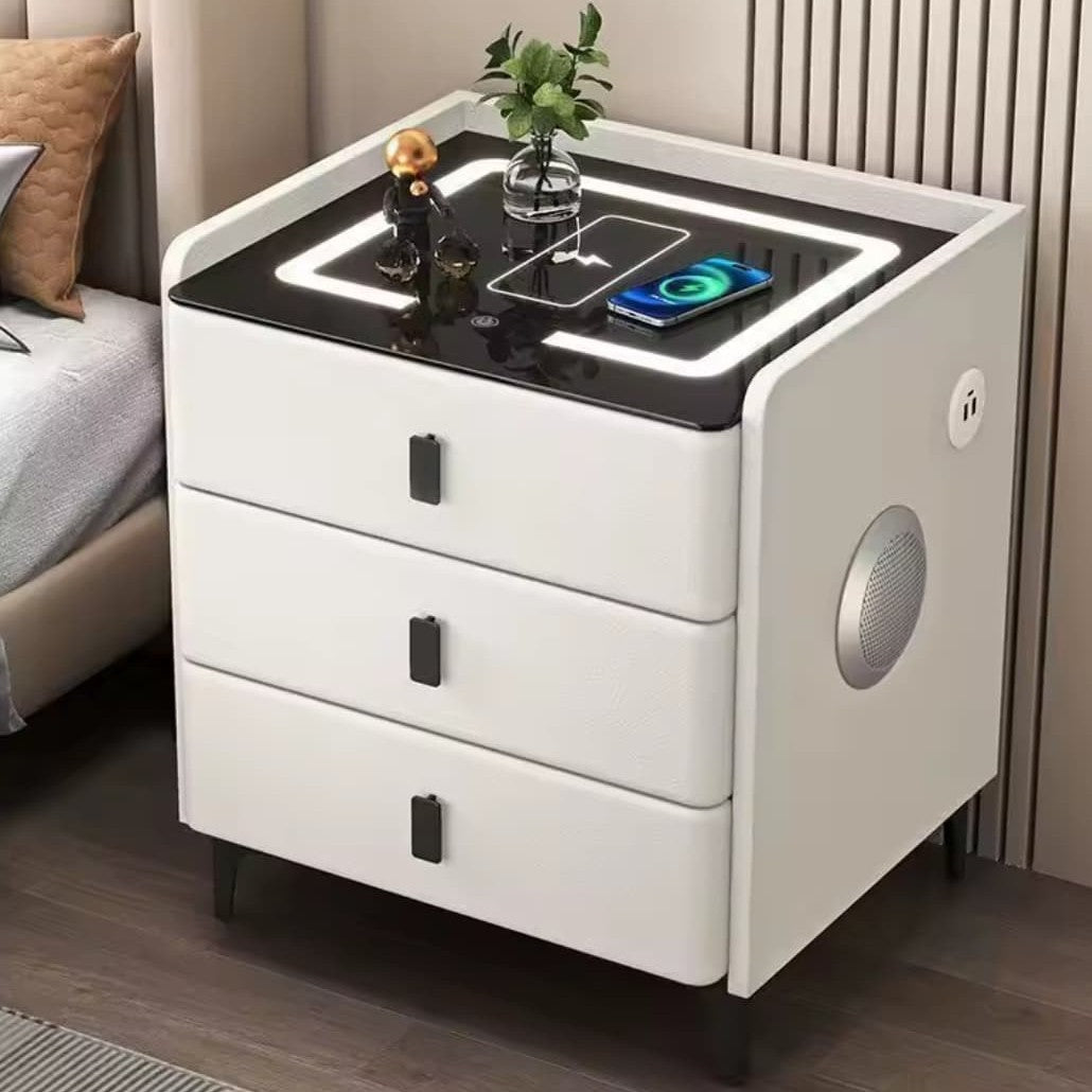 White smart bedside table measuring 60 × 40 × 50 cm with wireless charging, USB port, three color LED lighting, Bluetooth speaker, and three drawers.