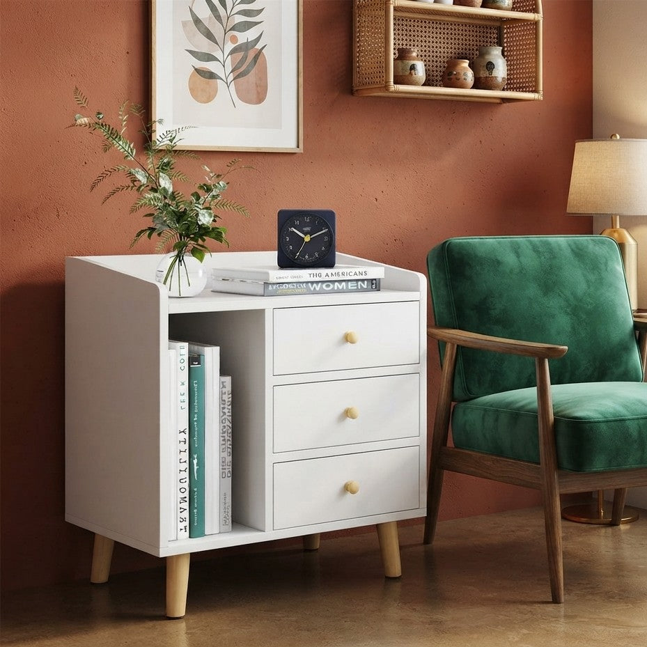 Modern white bedside table with three drawers, open bookshelf compartment, raised edge tabletop, and tapered wooden legs.