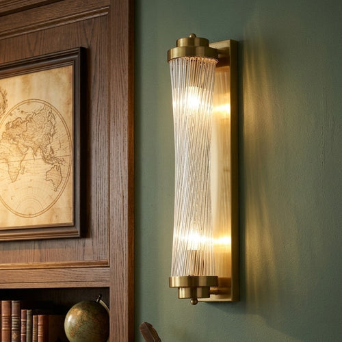 Modern brass cylindrical wall sconce with ribbed glass diffuser for elegant ambient lighting. 
