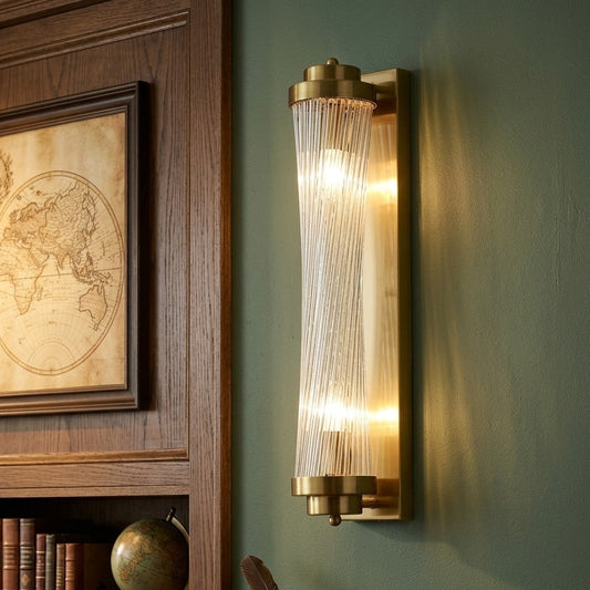 Modern brass cylindrical wall sconce with ribbed glass diffuser for elegant ambient lighting. 