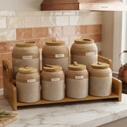 7 piece speckled ceramic spice jar set with wooden lids, leather loop handles, and a wooden display tray for stylish kitchen storage.