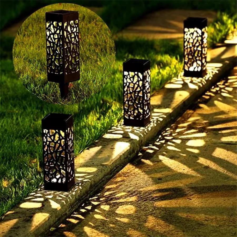 Modern solar powered pathway lights with cracked glass design, black pillar outdoor lamps casting warm decorative glow.