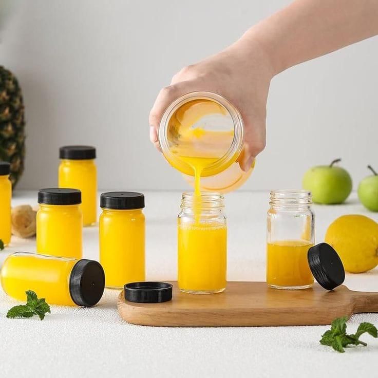 Set of six 60ml glass ginger shot bottles with black lids, cleaning brush, and stickers