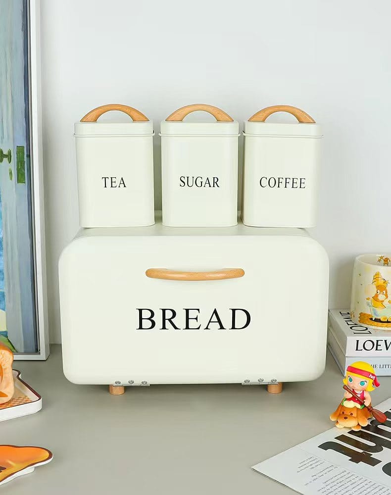 4-piece cream metal bread bin and canister set with natural wood handles, airtight lids, and stackable tea, sugar, and coffee containers for modern kitchen storage.