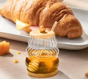 Glass honey dispenser jar with bamboo lid, base, and dipper.